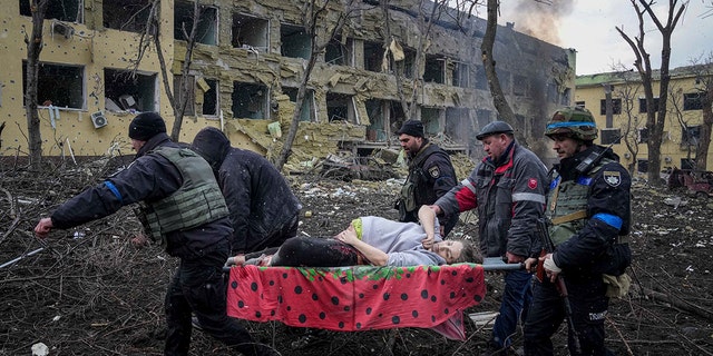 2022 年 3 月 9 日，星期三，乌克兰马里乌波尔，乌克兰急救人员和志愿者从一家因炮击而受损的妇产医院抬着一名受伤的孕妇。（美联社照片/Evgeniy Maloletka）