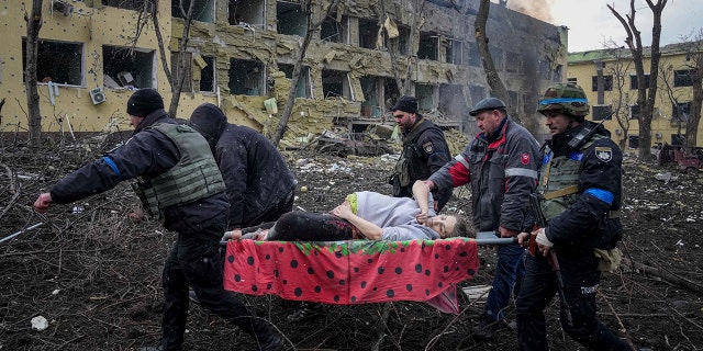 Ukrainian emergency employees and volunteers carry an injured pregnant woman from a maternity hospital damaged by shelling in Mariupol, Ukraine, Wednesday, March 9, 2022.