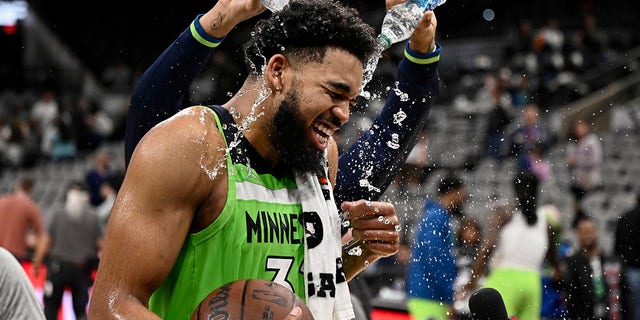 Minnesota Timberwolves center Karl-Anthony Towns is doused by teammate D'Angelo Russell, rear, after an NBA basketball game against the San Antonio Spurs on Monday, March 14, 2022, in San Antonio.