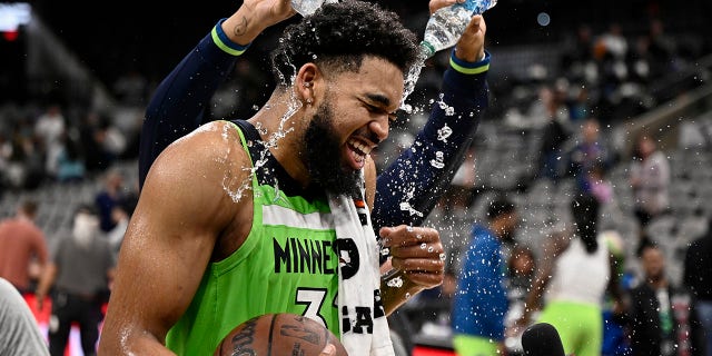 Minnesota Timberwolves center Karl-Anthony Towns is doused by teammate D'Angelo Russell, rear, after an NBA basketball game against the San Antonio Spurs on Monday, March 14, 2022, in San Antonio.