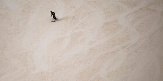 A skier descends at the Pizol ski resort on a slope partially covered with Sahara dust.