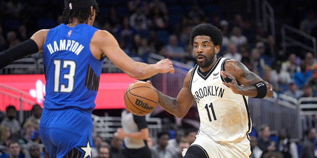 Brooklyn Nets guard Kyrie Irving (11) drives in front of Orlando Magic guard RJ Hampton (13) during the first half of the game on March 15, 2022 in Orlando, Fla. 