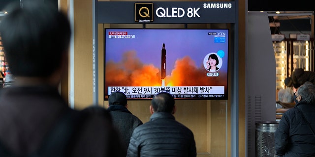 People watch a TV screen showing an information program about a North Korean missile with videos at a train station in Seoul, South Korea, on Wednesday, March 16, 2022.