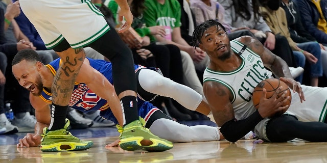 Golden State Warriors guard Stephen Curry, left, reacts after going for a loose ball next to Boston Celtics guard Marcus Smart during the first half of an NBA basketball game in San Francisco, Wednesday, March 16, 2022.