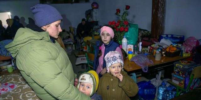 A woman and children are shown taking cover from shelling in a school bomb shelter in Sartana village, under the Gov. of the Donetsk People's Republic control, 11 miles northeast of Mariupol, eastern Ukraine, on March 16, 2022. 