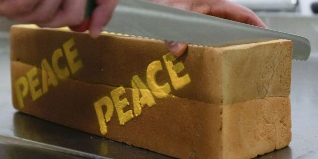Baker Matteo Cunsolo slices a square loaf of 'peace bread' in his laboratory in Parabiago.