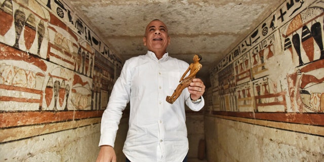 Mostafa Waziri, Secretary General of the Supreme Council of Antiquities, displays a small statue at a tomb decorated with hieroglyphic inscriptions at a recently discovered tomb near the famous Step Pyramid, in Saqqara, south of Cairo, Egypt, Saturday, March 19, 2022.