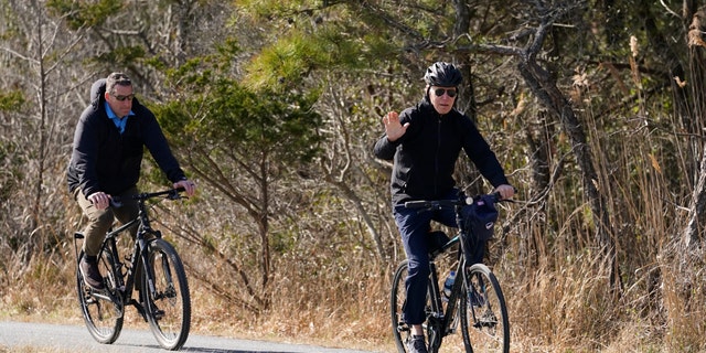President Joe Biden waves to media as he rides a bicycle in Gordon's Pond State Park in Rehoboth Beach, Del., Sunday, March 20, 2022. (AP Photo/Carolyn Kaster)