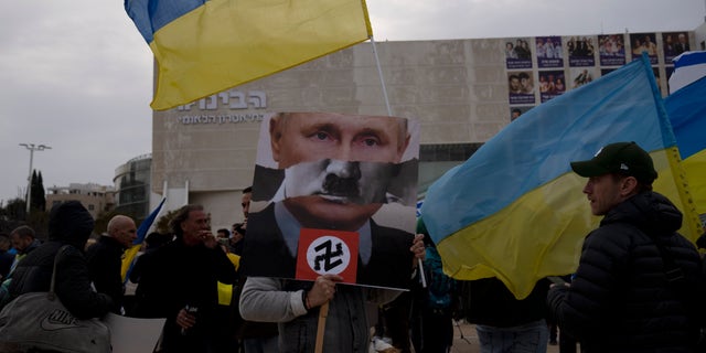 A protester in Habima Square holds a depiction of Russian President Vladimir Putin in Tel Aviv, Israel.
