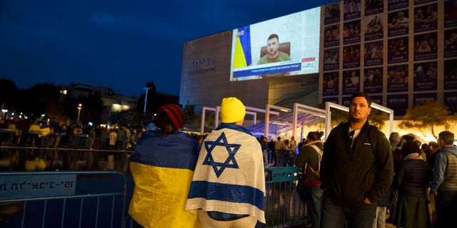 People gather in Habima Square in Tel Aviv, Israel, to watch Ukrainian President Volodymyr Zelenskyy in a video address to the Knesset, Israel's parliament.