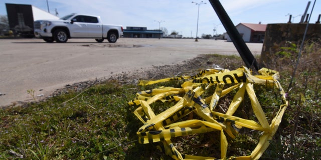 Crime scene tape lies on the ground, Sunday, March 20, 2022 at the scene where a shooting that left over 20 injured and one dead occurred Saturday night in Dumas, Ark.