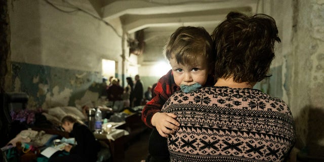 A woman holds a baby in a makeshift bomb shelter in Mariupol, Ukraine on Monday, March 7, 2022. 