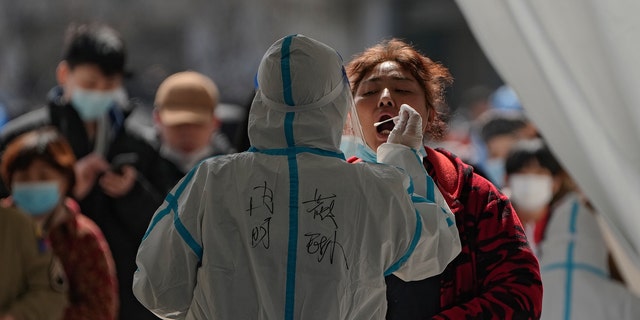 A woman gets a coronavirus test at an outdoor testing site Monday, March 21, 2022, in Beijing, China. 