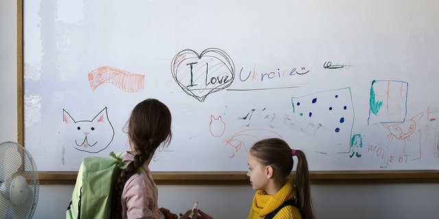 Two refugee children from the Ukraine stand in front of a white board before their classes start in Berlin, Germany, Monday, March 21, 2022. 