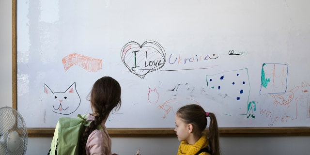 Two refugee children from the Ukraine stand in front of a white board before their classes start in Berlin, Germany, Monday, March 21, 2022. 