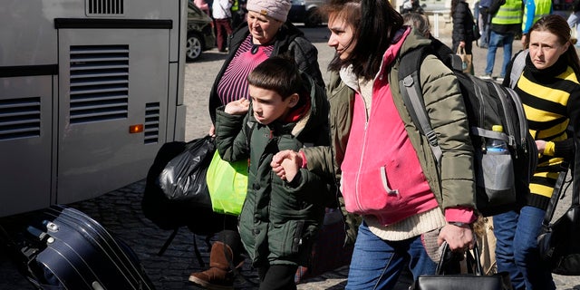 Ukrainian refugees with children board transport at a square next to a railway station in Przemysl, Poland, on Tuesday, March 22, 2022. 