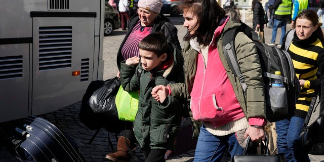 Ukrainian refugees with children board transport at a square next to a railway station in Przemysl, Poland, on Tuesday, March 22, 2022. 