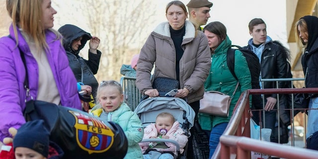 پناهجویان با کودکان پس از فرار از جنگ از اوکراین همسایه در ایستگاه راه آهن در پرزمیسل، لهستان، در روز سه شنبه، 22 مارس 2022، راه می روند. 