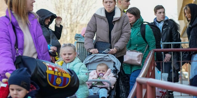 Refugees with children walk after fleeing the war from neighboring Ukraine at a railway station in Przemysl, Poland, on Tuesday, March 22, 2022. 