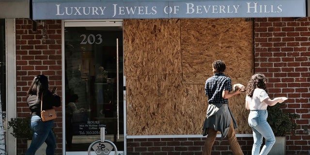 Pedestrians walk past a barricaded Luxury Jewels of Beverly Hills.  Los Angeles police are warning people that wearing expensive jewelry in public could make them a target for thieves – a note of caution as thefts are on the rise across the city. 