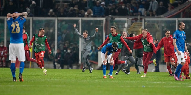 North Macedonia players celebrate as Italy players reacts after their team's elimination at the end of the World Cup qualifying play-off soccer match between Italy and North Macedonia, at Renzo Barbera stadium, in Palermo, 이탈리아, 목요일, 행진 24, 2022. North Macedonia won 1-0.
