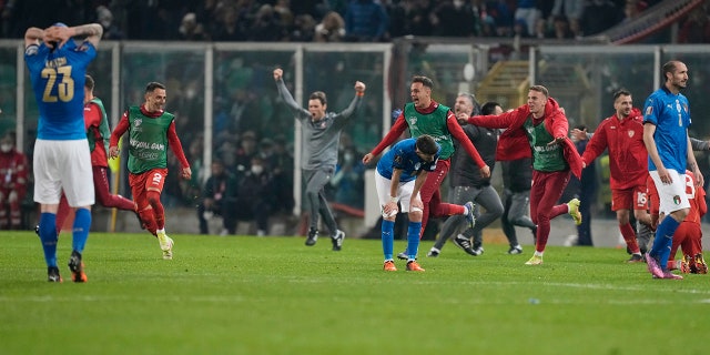 North Macedonia players celebrate as Italy players reacts after their team's elimination at the end of the World Cup qualifying play-off soccer match between Italy and North Macedonia, at Renzo Barbera stadium, in Palermo, Italy, Thursday, March 24, 2022. North Macedonia won 1-0.
