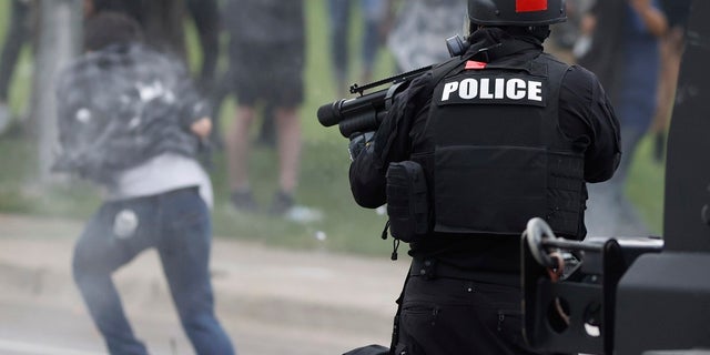 FILE - In this May 30, 2020 photo, a Denver police officer shoots a pepper ball toward a man as he retreats during a protest outside the State Capitol over the death of George Floyd in Denver.
