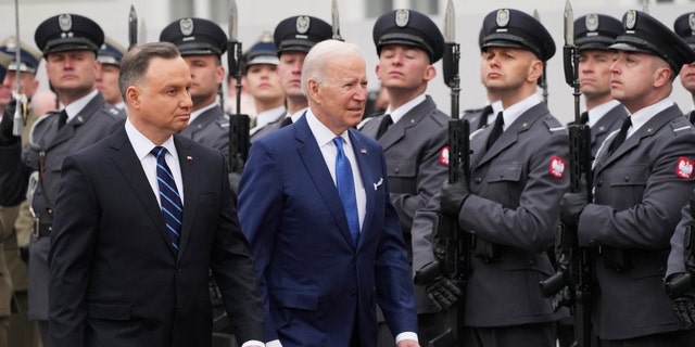Prezydent Biden, centrum i prezydent Polski Andrzej Duda przechodzą obok gwardii honorowej podczas wojskowej ceremonii powitania w Pałacu Prezydenckim w Warszawie, sobota, 26 marca 2022 r.