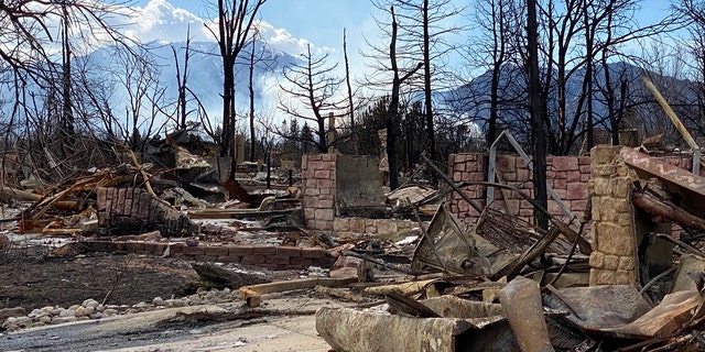 This photo provided by realtor Alicia Miller shows the ruins of Miller's former house, which burned to the ground on Dec. 30, 2021, in the devastating Marshall Fire that roared through Louisville, Colo., as smoke from the NCAR Fire burns, Saturday, March 26, 2022, in the background. (Alicia Miller via AP)