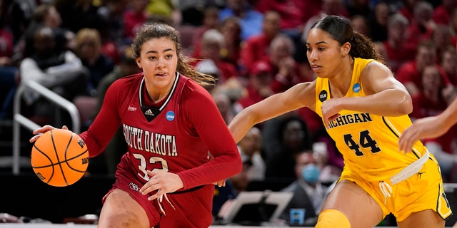 South Dakota's Kyah Watson (32) drives to the basket as Michigan's Cameron Williams (44) defends during the first half of a game in the Sweet 16 round of the NCAA women's tournament Saturday, March 26, 2022, in Wichita, Kan. 