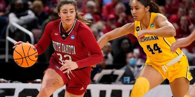 South Dakota's Kyah Watson (32) drives to the basket as Michigan's Cameron Williams (44) defends during the first half of a game in the Sweet 16 round of the NCAA women's tournament Saturday, March 26, 2022, in Wichita, Kan.