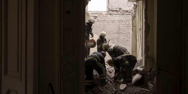 Emergency workers search for bodies under the debris of the regional administration building, heavily damaged after a Russian attack earlier this month in Kharkiv, Ukraine, Sunday, March 27, 2022.