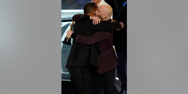 Will Smith and John Travolta hug in the audience as Will Smith is announced the winner of the award for best performance by an actor in a leading role for "King Richard" at the Oscars on Sunday, March 27, 2022. (AP Photo/Chris Pizzello)