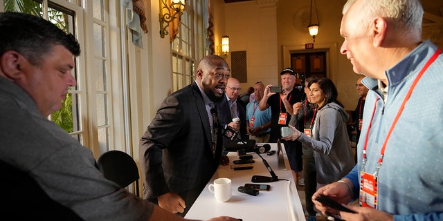 Pittsburgh Steelers football head coach Mike Tomlin, second left, arrives to speak to journalists at a coaches press availability during the NFL owner's meeting, Monday, March 28, 2022, at The Breakers resort in Palm Beach, Fla.