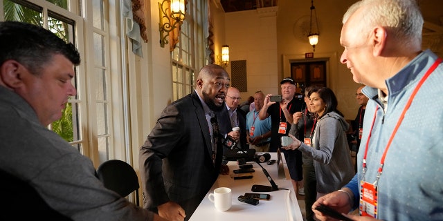 Pittsburgh Steelers football head coach Mike Tomlin, second left, arrives to speak to journalists at a coaches press availability during the NFL owner's meeting, Monday, March 28, 2022, at The Breakers resort in Palm Beach, Fla.