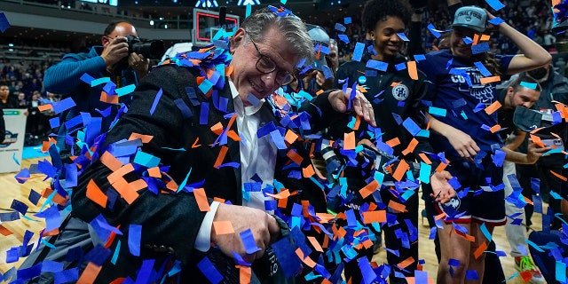Connecticut head coach Geno Auriemma celebrates with players after defeating NC State in double overtime in the East Regional final college basketball game of the NCAA women's tournament, Monday, March 28, 2022, in Bridgeport, Conn.