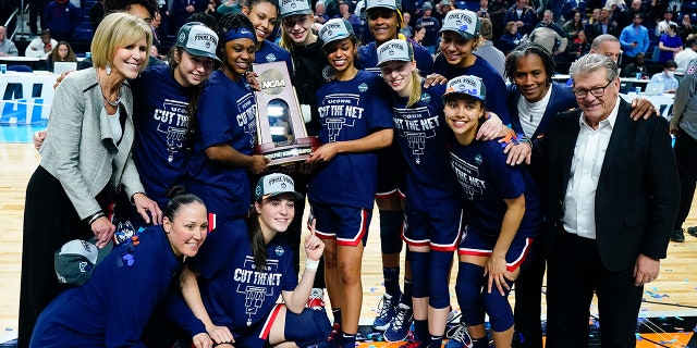 Connecticut players hold up the East Region championship trophy after defeating NC State in the East Regional final college basketball game of the NCAA women's tournament, Monday, March 28, 2022, in Bridgeport, Conn.