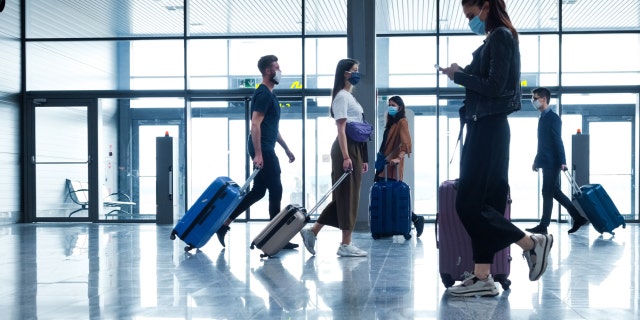 People traveling by plane during the coronavirus pandemic have been shown to be wearing face masks while walking through the airport terminal. 