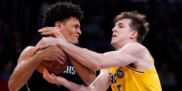 Dallas Mavericks guard Josh Green, left, and Los Angeles Lakers guard Austin Reaves grapple for the ball during the first half of an NBA basketball game Tuesday, March 1, 2022, in Los Angeles.