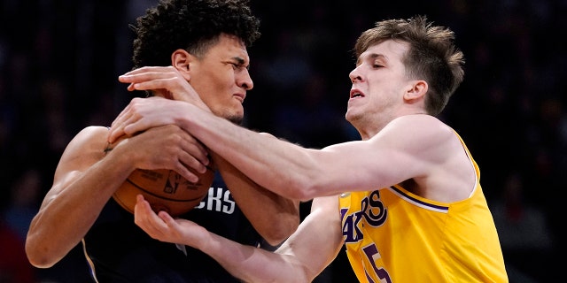 Dallas Mavericks guard Josh Green, left, and Los Angeles Lakers guard Austin Reaves grapple for the ball during the first half of an NBA basketball game Tuesday, March 1, 2022, in Los Angeles.
