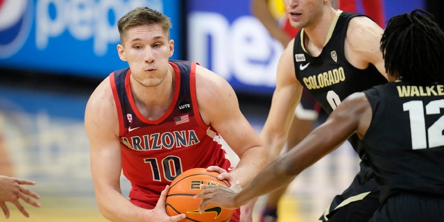 Arizona forward Azuolas Tubelis, left, drives the lane as Colorado guard Luke O'Brien, center, and forward Jabari Walker, right, defend in the first half of an NCAA college basketball game Saturday, Feb. 26, 2022, in Boulder, Colo.