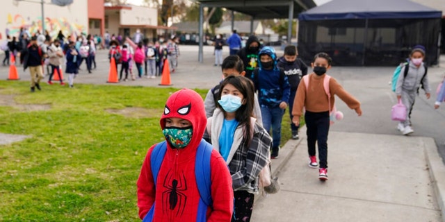 FILE - Students walk to class amid the COVID-19 pandemic at Washington Elementary School Jan. 12, 2022, in Lynwood, Calif. The governors of California, Oregon and Washington have announced that schoolchildren will no longer required to wear masks starting March 12, 2022. The governors of the three states announced the measure in a joint statement as part of new indoor mask policies that come as coronavirus case and hospitalization rates decline across the West Coast. 