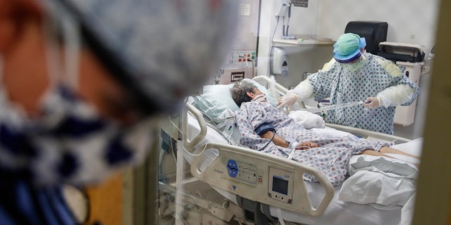 FILE - In this April 20, 2020, file photo, resident physician Leslie Bottrell stands outside a room at an Intensive Care Unit as a nurse suctions the lungs of a COVID-19 patient at St. Joseph's Hospital in Yonkers, N.Y. 