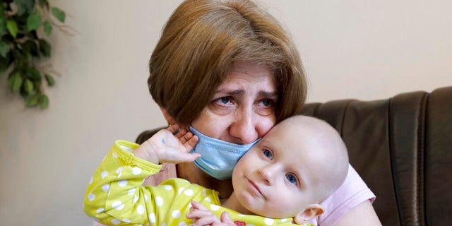 Nadia Kryminec holds her 22-month-old granddaughter Yeva Vakulenko, who has leukemia, at a clinic in Bocheniec, Poland, on Thursday, March 17, 2022.