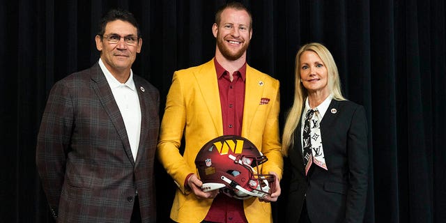 Washington Commanders NFL football team new quarterback Carson Wentz is flanked by team co-owner and co-CEO Tanya Snyder and head coach Ron Rivera as they pose for a picture after Wentz was introduced during a news conference in Ashburn, Va., Thursday, March 17, 2022.