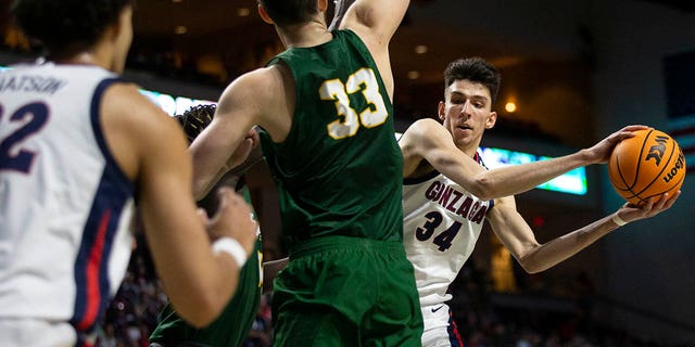 Gonzaga center Chet Holmgren (34) passes to forward Anton Watson (22) while San Francisco center Volodymyr Markovetskyy (33) guards during the first half of the West Coast Conference tournament semifinal Monday, March 7, 2022, in Las Vegas.