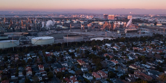 An aerial image taken on Jan. 24, 2022, shows storage tanks at the Chevron Products Company El Segundo Refinery adjacent to homes at sunset in Manhattan Beach, California. 