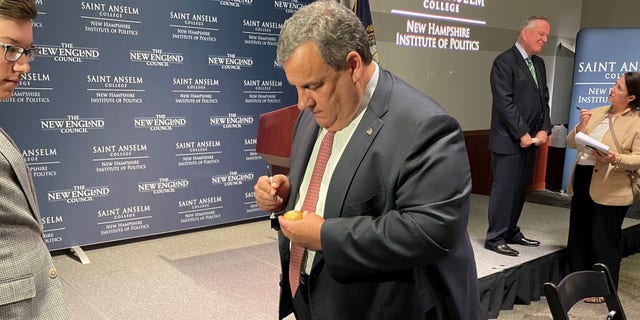 Former New Jersey Gov. Chris Christie signs the iconic wooden eggs after speaking at 'Politics and Eggs' at the New Hampshire Institute of Politics at Saint Anselm College, on March 21, 2022 in Goffstown, N.H.