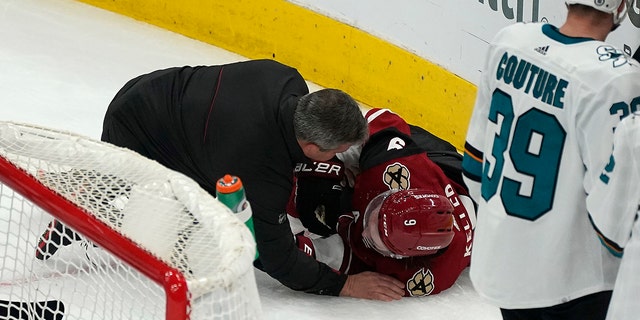 A trainer attends to Arizona Coyotes' Clayton Keller, 9, who collided with the boards during the third stint of the team's NHL hockey game against the San Jose Sharks, Wednesday, March 30, 2022, in Glendale, Arizona.