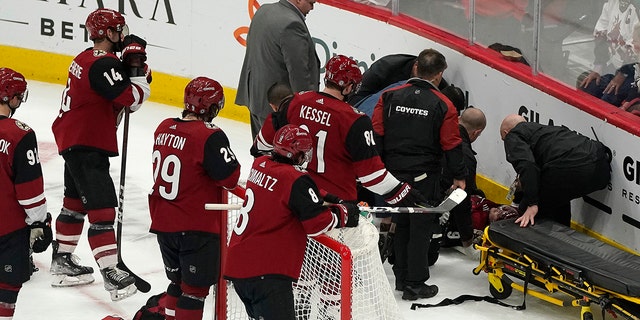 Arizona Coyotes watch as medical personnel and team officials attend to Clayton Keller, who crashed into the boards during the third period of the team's NHL hockey game against the San Jose Sharks, Wednesday, March 30, 2022, in Glendale, Arizona.